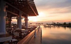a restaurant with tables and chairs on the water at sunset at Strand Beach Resort in Taba