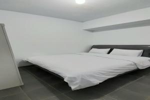 Cama blanca con sábanas y almohadas blancas en SPOT ON 92236 Kediri Family Homestay, en Medan