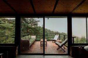 un soggiorno con divano e sedie su un balcone di Cedar Scent Guesthouse a Batroûn
