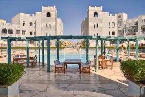Fanadir Hotel El Gouna في الغردقة: فناء مع طاولة وكراسي بجوار حمام سباحة
