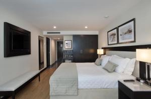 a bedroom with a large white bed and a flat screen tv at Miramar By Windsor Copacabana in Rio de Janeiro