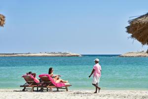 eine Gruppe von Menschen, die am Strand auf Stühlen sitzen in der Unterkunft Juweira Boutique Hotel Adult only in Salalah