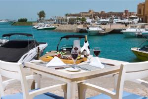 a table with wine glasses and a boat in the water at Captain's Inn Hotel in Hurghada