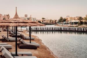een strand met stoelen en parasols naast een waterlichaam bij Cook’s Club El Gouna (Adults Only) in Hurghada