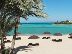 una playa con sillas y sombrillas y el océano en The Chedi El Gouna, en Hurghada