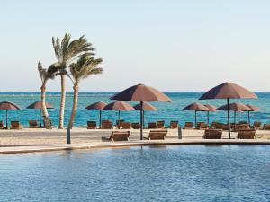 a swimming pool with chairs and umbrellas on the beach at The Chedi El Gouna in Hurghada