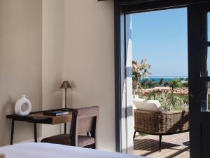 a bedroom with a bed and a desk and a balcony at The Chedi El Gouna in Hurghada