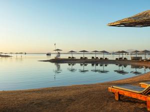 a beach with a pool of water with umbrellas at Club Paradisio El Gouna Red Sea in Hurghada