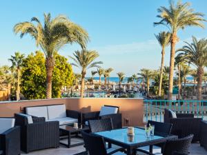 d'une terrasse avec des tables, des chaises et des palmiers. dans l'établissement Club Paradisio El Gouna Red Sea, à Hurghada
