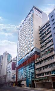 a tall building with glass windows in a city at Lodgewood by Nina Hospitality Mong Kok in Hong Kong
