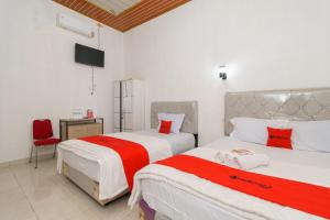 1 Schlafzimmer mit 2 Betten mit roter und weißer Bettwäsche in der Unterkunft RedDoorz @ Jalan Sultan Agung Lampung in Kedaton