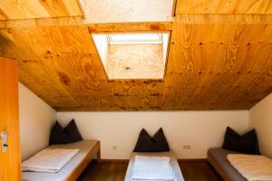 two beds in a room with a wooden ceiling at Jugendherberge Schliersee in Schliersee