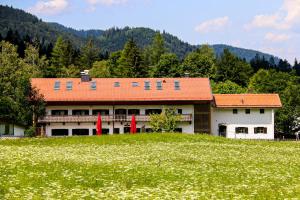 a building with an orange roof in a field at Jugendherberge Schliersee in Schliersee