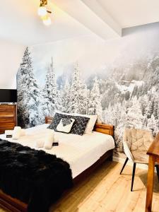 a bedroom with a snow covered forest mural on the wall at Willa Tulula in Kościelisko