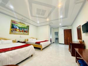 a hotel room with two beds and a tv at Khách sạn Hưng Việt (Măng Đen) in Kon Tum