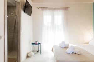 a white bedroom with a bed and a television at Seadrop Suites in Lefkada Town