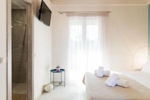a white bedroom with a bed and a television at Seadrop Suites in Lefkada
