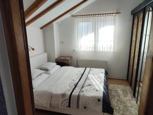 a white bedroom with a bed and a window at Apartman Lara in Krapina