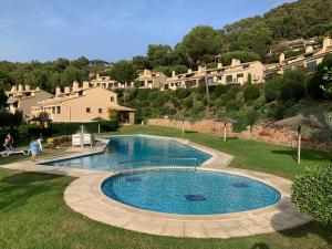 una piscina en un patio con casas al fondo en Magnifique Villa avec vue mer 8 personnes, en Llafranc