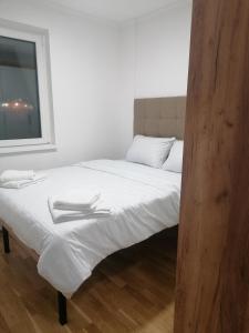 une chambre avec un lit avec des draps blancs et une fenêtre dans l'établissement Sunčana Planina Kopaonik, à Kopaonik