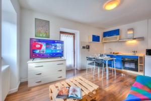 een woonkamer met een tv en een keuken met blauwe kasten bij Casa Umberto - Happy Rentals in Tenno