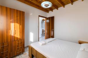 Un dormitorio con una cama blanca y un armario de madera. en Stegna Silence Seaview, en Archangelos