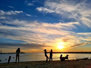 um grupo de pessoas de pé na praia ao pôr do sol em Lapin 9 - By Beach Apartments TLV em Tel Aviv