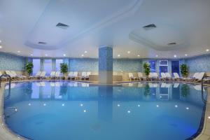 uma grande piscina num hotel com cadeiras e mesas em Palan Ski & Convention Resort Hotel em Erzurum