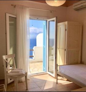 a bedroom with a bed and a chair and a window at Mykonos Dot - The Villas in Mikonos