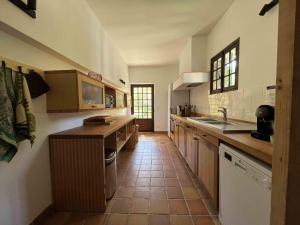a kitchen with wooden cabinets and a tile floor at Gite la Tuilerie 46 in Tour-de-Faure