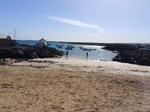 twee mensen staan op een strand met boten in het water bij Emily Home in Parque Holandes