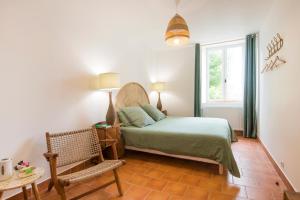 a bedroom with a bed and a chair and a window at le Jardin de Josnes in Josnes
