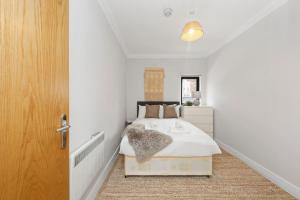 a white bedroom with a bed and a wooden door at Amazing 2bed flat 10min to Wimbledon tennis courts in London