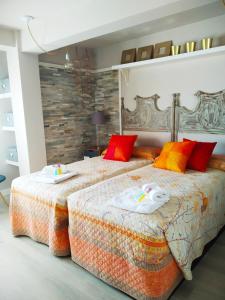 two beds in a bedroom with red and orange pillows at LA CORTE LUXURY ARENA, con terraza a 15 mtr de la playa in Gijón