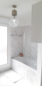 a white bathroom with a tub and a window at La Terrasse - big apartment & terrace 80m2 - metro 17 min from Paris in Bagneux