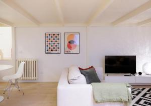een witte woonkamer met een witte bank en een tv bij [NAVIGLI-BOCCONI] SPAZIO LUCE DESIGN in Milaan