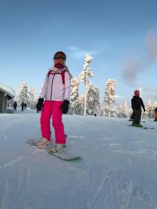 a girl is standing on a snowboard in the snow at Beautiful lakeside Villa Vetojärvi in Pennala