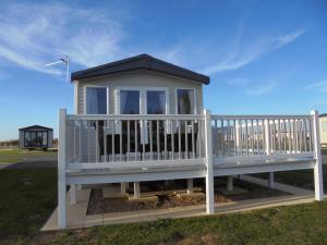 ein kleines Haus mit einer Veranda und einem Geländer in der Unterkunft 6 Berth Grange Leisure Park Mablethorpe Stonewood in Mablethorpe