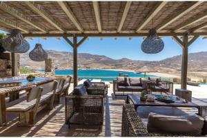un patio con mesas y sillas y vistas al océano en Elite Mykonos Villa - Villa Roxane - Private Pool - 6 Bedrooms - Beachfront - Ftelia en Dexamenes
