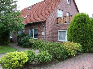 ein Backsteinhaus mit einer Terrasse darüber in der Unterkunft Pension Kraus in Esens