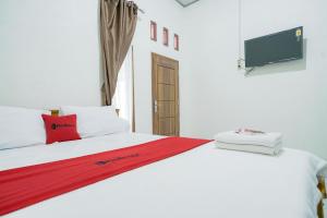 a bedroom with a white bed with a tv on the wall at RedDoorz @ Seputih Jaya Lampung in Gunungsugih