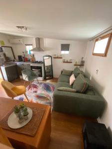 Bungalow de charme في لا سالين لو باين: غرفة معيشة مع أريكة خضراء وطاولة
