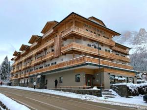 un grand bâtiment sur le côté d'une route dans l'établissement Hotel Colfosco, à San Martino di Castrozza