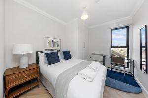 a white bedroom with a bed and a desk and a window at Pleasing 2bed flat 10min to Wimbledon tennis court in London