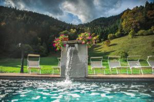 eine Gruppe von Stühlen, die um einen Pool mit einem Brunnen herum sitzen in der Unterkunft Rustico Pastoria in Lenzumo di Concei