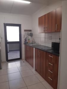 a kitchen with wooden cabinets and a window in it at Aspasia Agency CC in Mariental