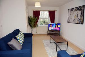 un salon avec un canapé bleu et une télévision dans l'établissement Charming 3 Bed House in Bristol, à Bristol