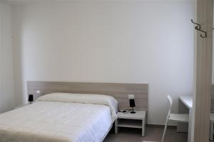 una camera da letto con un letto bianco, una scrivania e una sedia di Verde Blu Vacanze Suites a Porto Cesareo