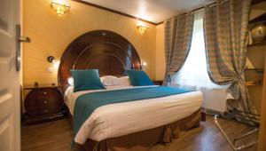 a bedroom with a large bed with a wooden headboard at Ault - Villa Aultia Hotel - baie de somme in Ault