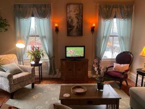 ein Wohnzimmer mit einem TV, einem Sofa und Stühlen in der Unterkunft 1 Br Private Victorian Apt in convenient City location on 5 acre, sleeps 4 in Poughkeepsie